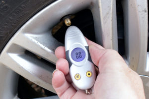 Woman checking tyre pressure with a digital gauge