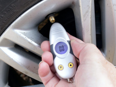 Woman checking tyre pressure with a digital gauge