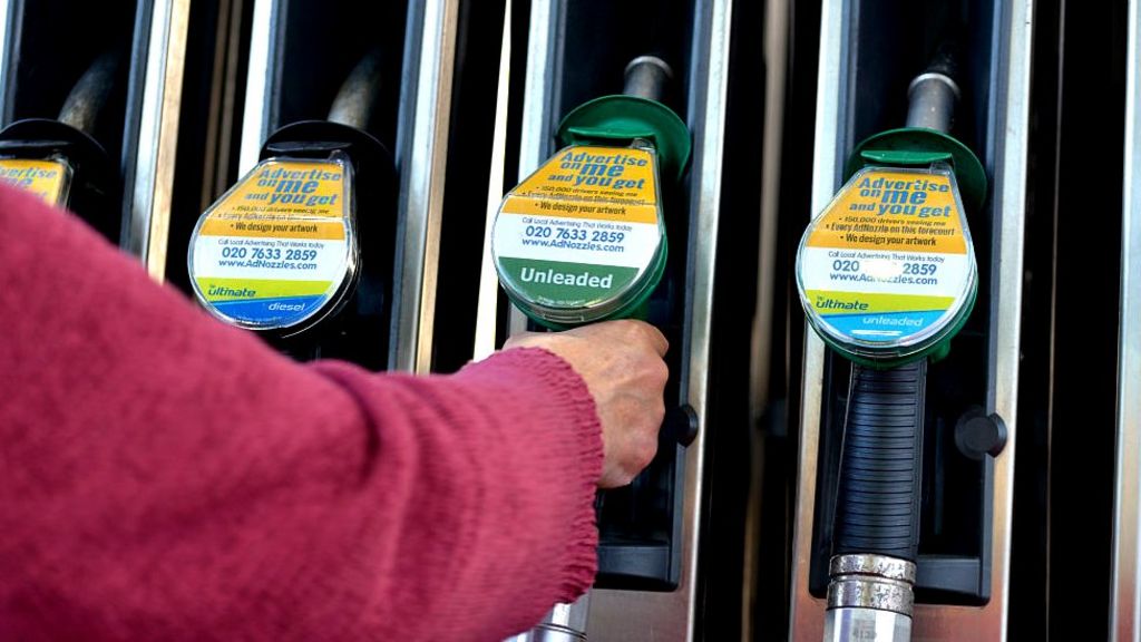 Woman selecting unleaded petrol at the pump